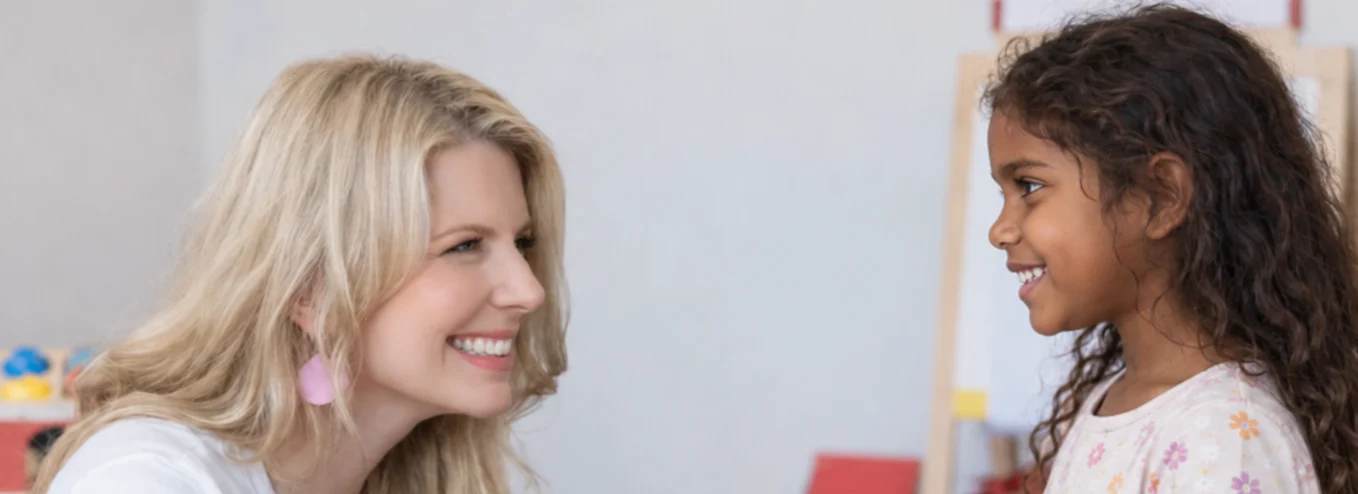 Meg Hughes and a young girl smiling at each other during a play session