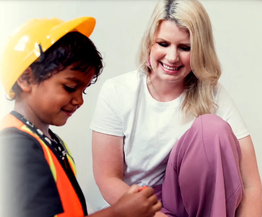 Meg Hughes smiling beside a young child in a hard hat